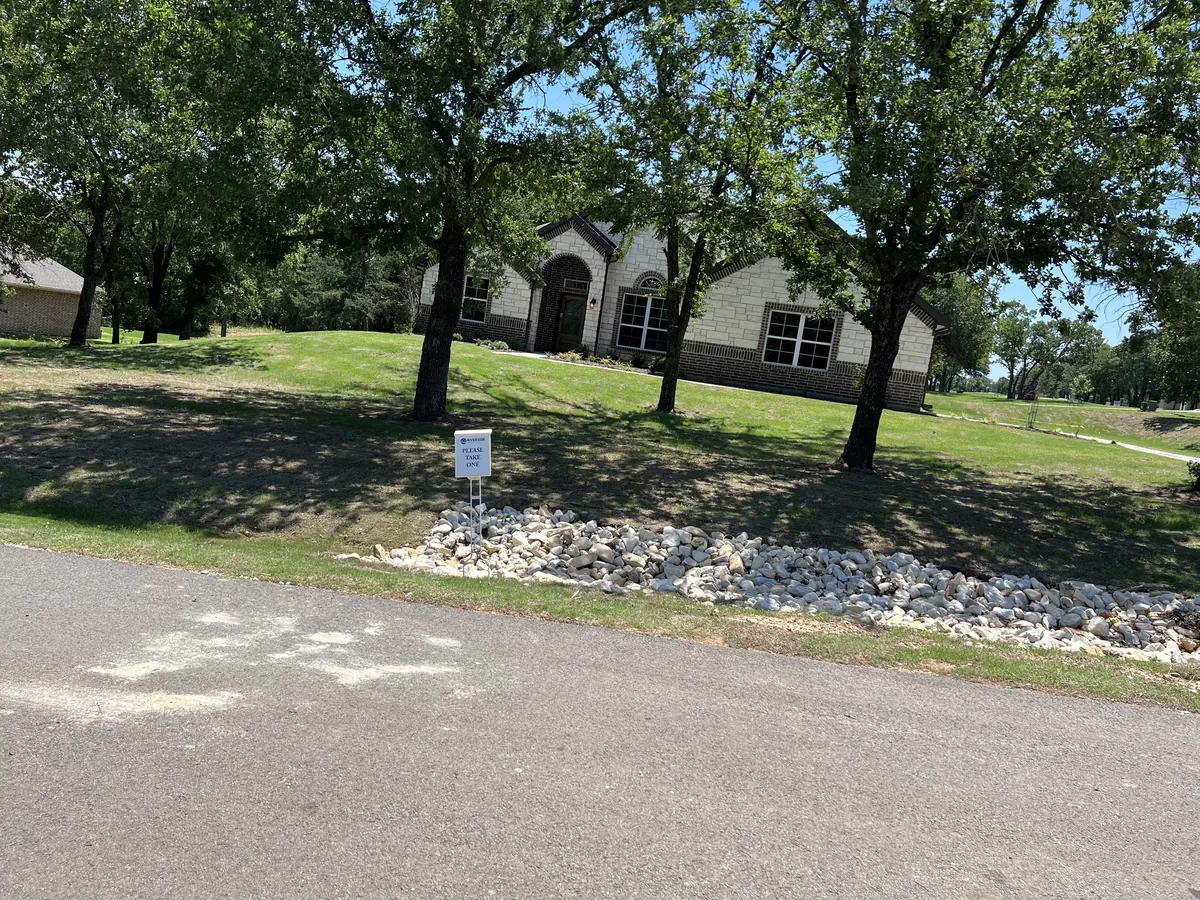 Decorative white rock border along a driveway under mature trees