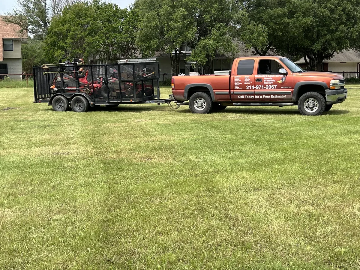 Pickup truck with a dump trailer parked on a mowed lawn